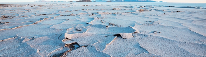 Zoutvlakte Salar de Uyuni in Bolivia met gebarsten zoutkorst en bergen aan de horizon.