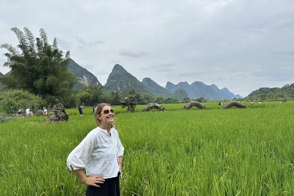 Reiziger in rijstveld met karstbergen in de achtergrond tijdens groepsrondreis China Hoogtepunten (17 dagen).