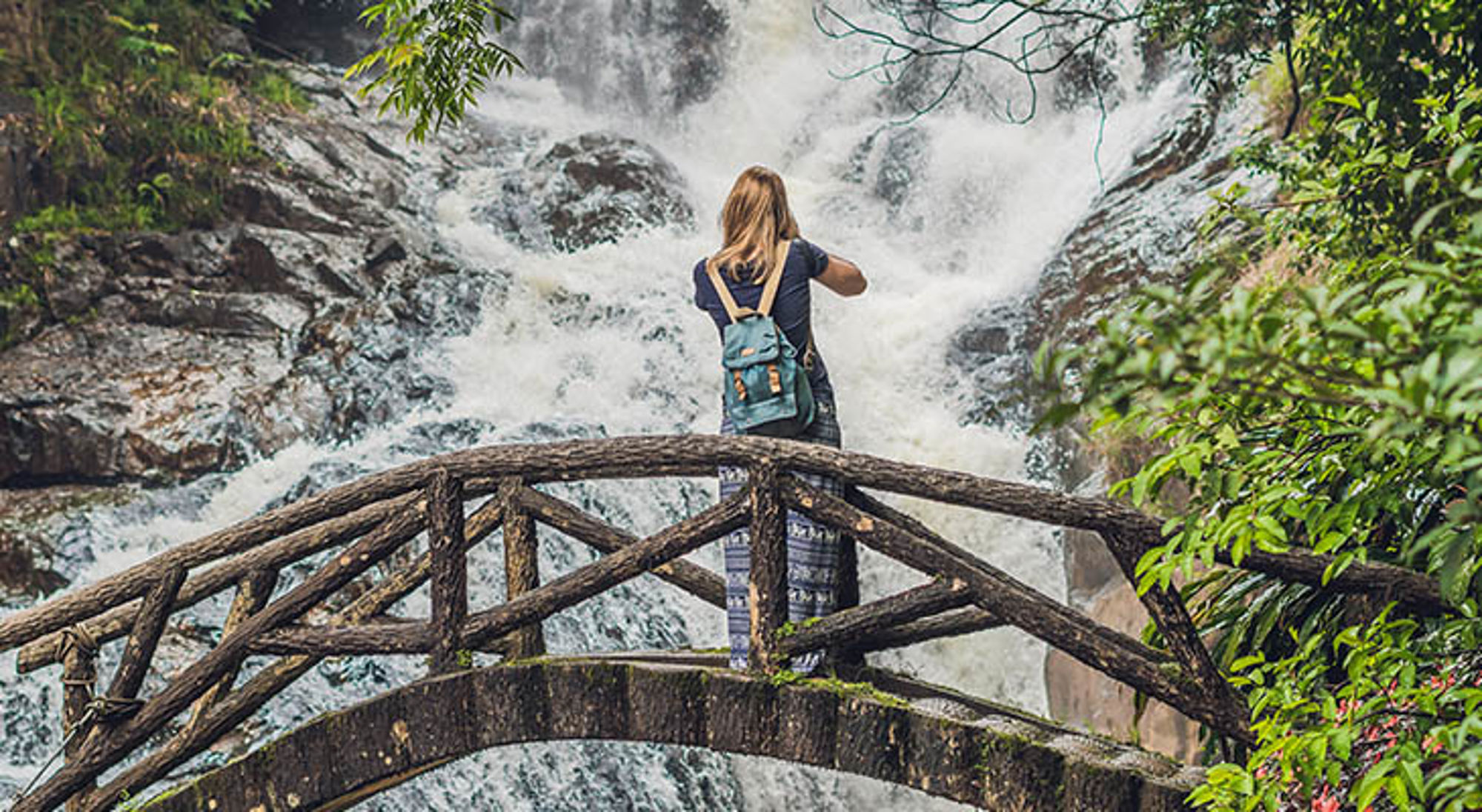 Toerist met rugzak op brug bij waterval in Vietnam.