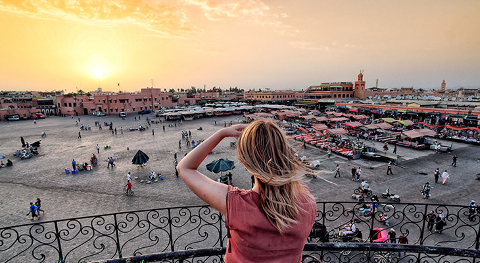 Uitzicht op het Jemaa el-Fna-plein in Marrakech bij zonsondergang, met marktkramen en bezoekers.