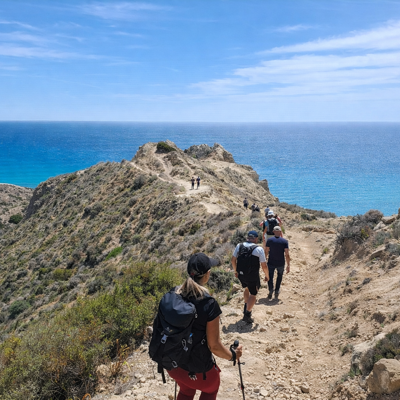 Wandelaars op een kustpad met uitzicht op de blauwe zee tijdens een wandelvakantie op Cyprus.