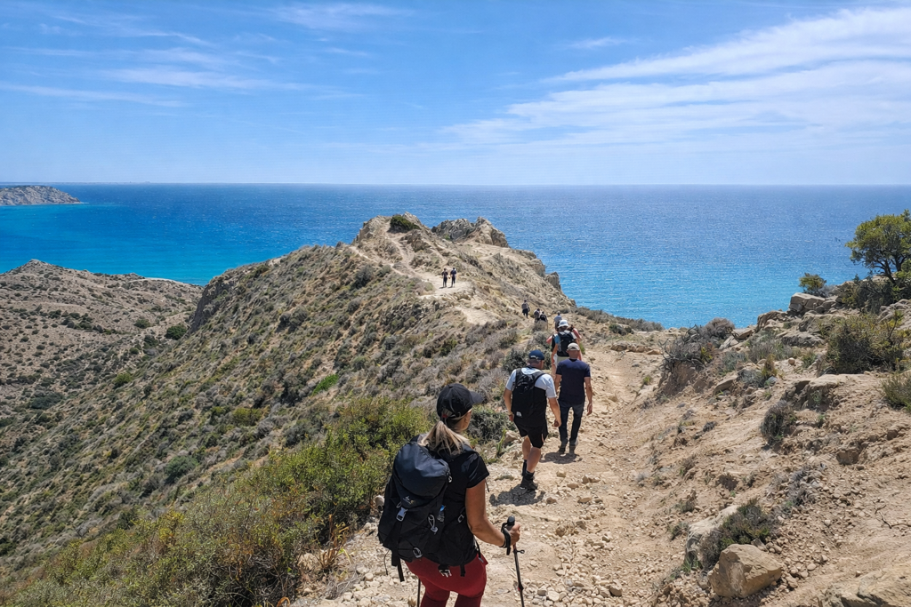 Wandelaars op een kustpad met uitzicht op de blauwe zee tijdens een wandelvakantie op Cyprus.