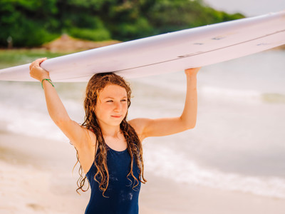 Meisje met surfboard op het strand tijdens Route Thailand, dag 18.
