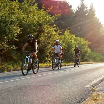 Groep fietsers tijdens fietsvakantie op de Balkan, met uitzicht op een historische stad.