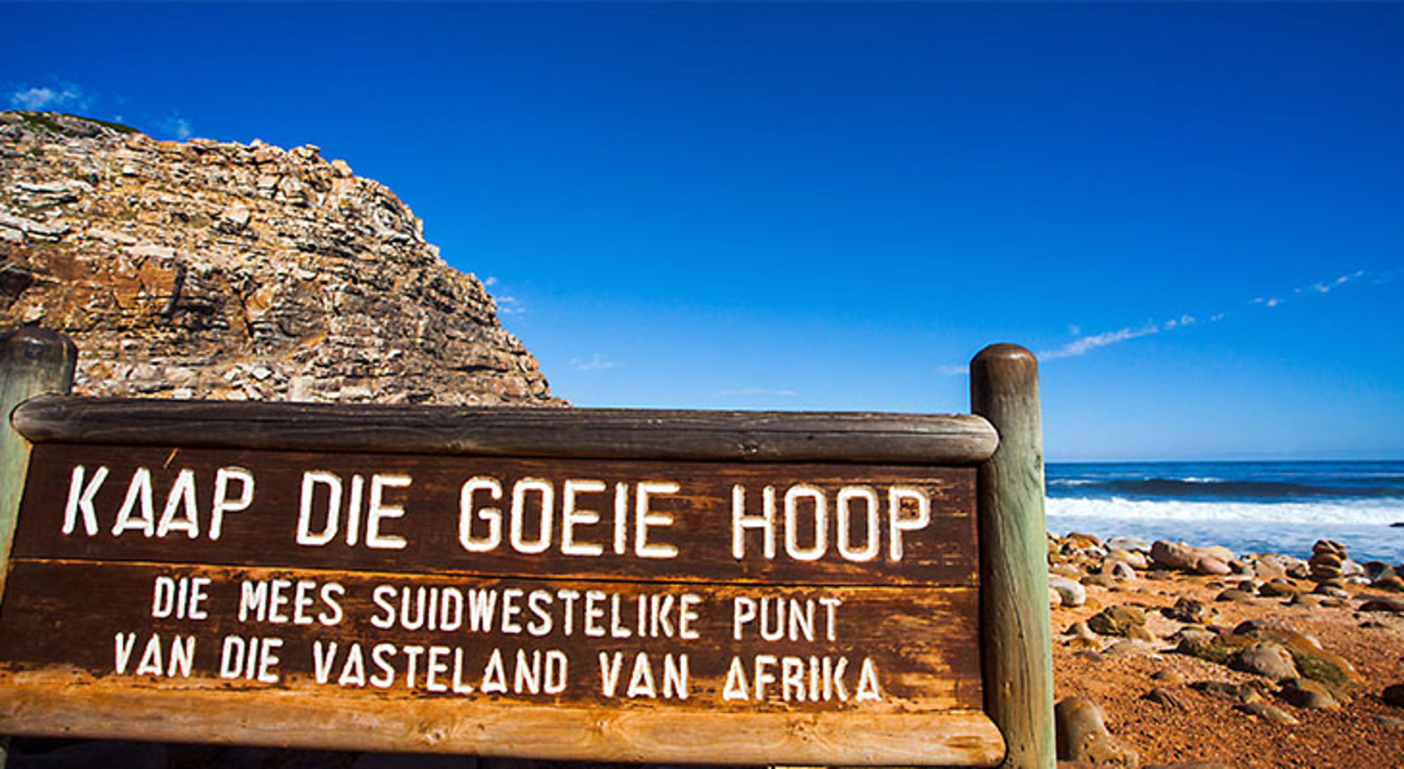 Houten bord met “Kaap die Goeie Hoop” bij de rotskust en oceaan in Zuid-Afrika.