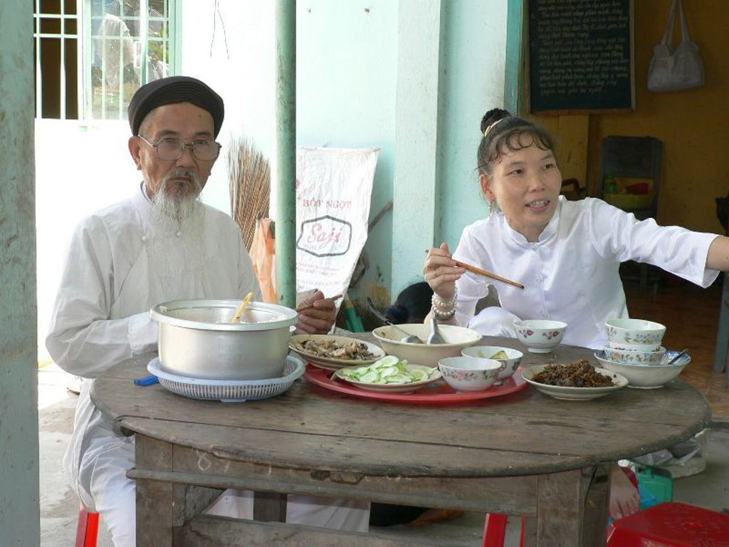 Twee locals eten samen aan een tafel met Vietnamese gerechten tijdens een 22-35ers reis Vietnam.
