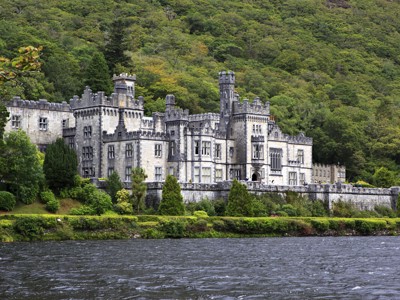 Kylemore Abbey aan de oever van een meer, omringd door groene heuvels in Ierland.