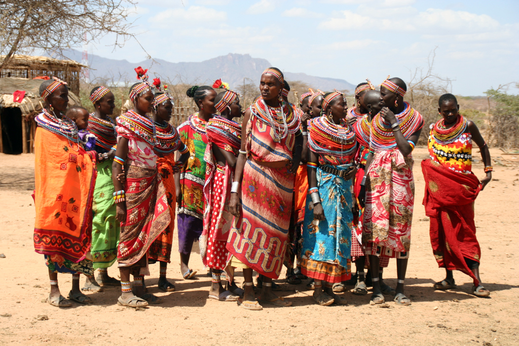 Groep Samburu-vrouwen in kleurrijke kleding en kralensieraden tijdens een bezoek in Kenia.