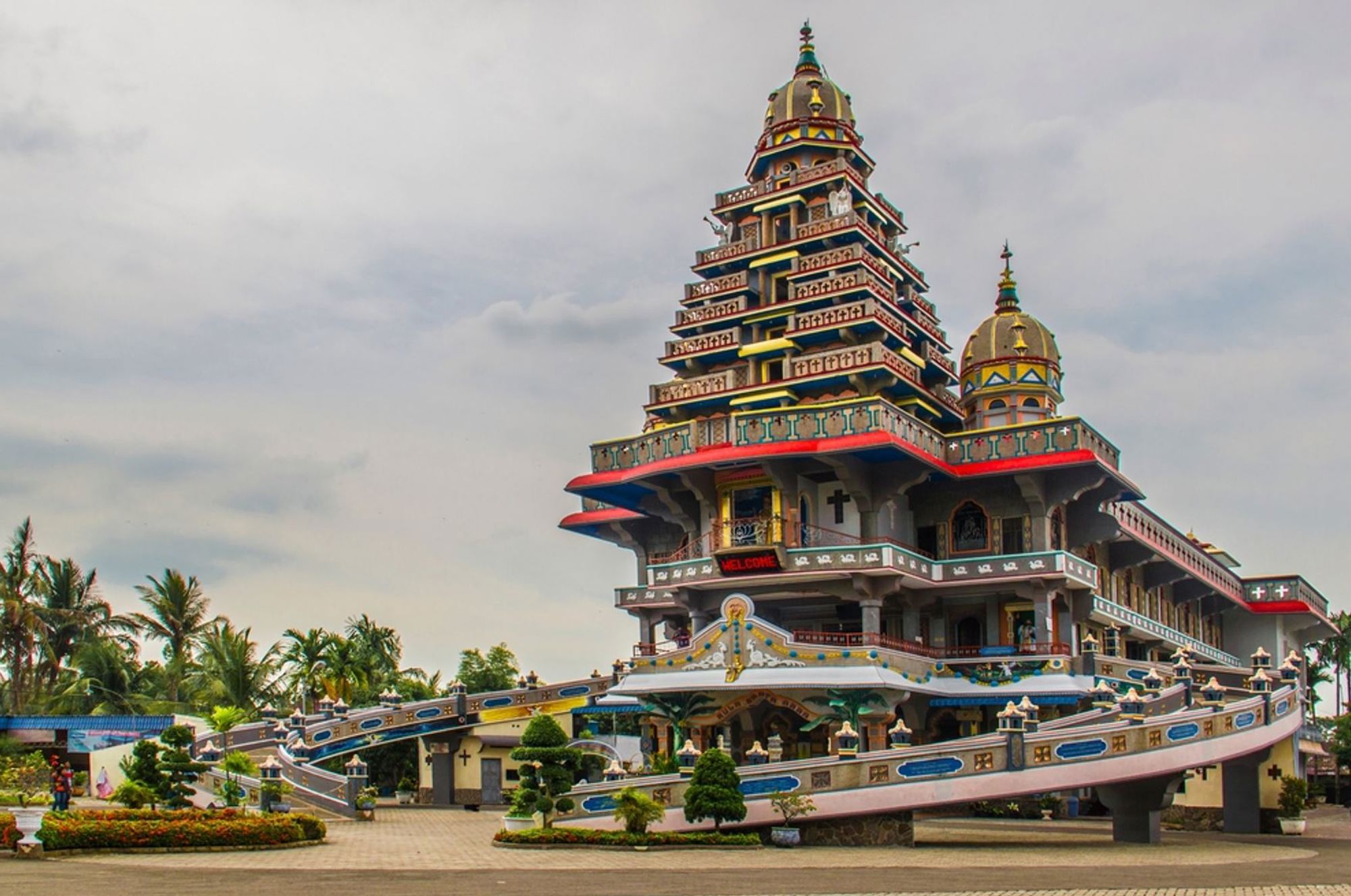 Kleurrijke, meerlaagse boeddhistische tempel in Indonesië met pagodevormige toren en koepels.
