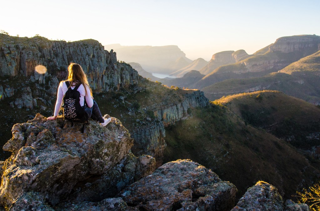 Reiziger met rugzak op rotsrand met uitzicht over de Blyde River Canyon tijdens een 22-35ers reis Zuid-Afrika.