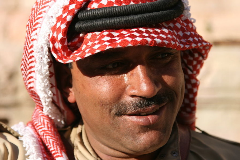 Portret van een man met rood-witte keffiyeh in Jordanië, tijdens een groepsrondreis.