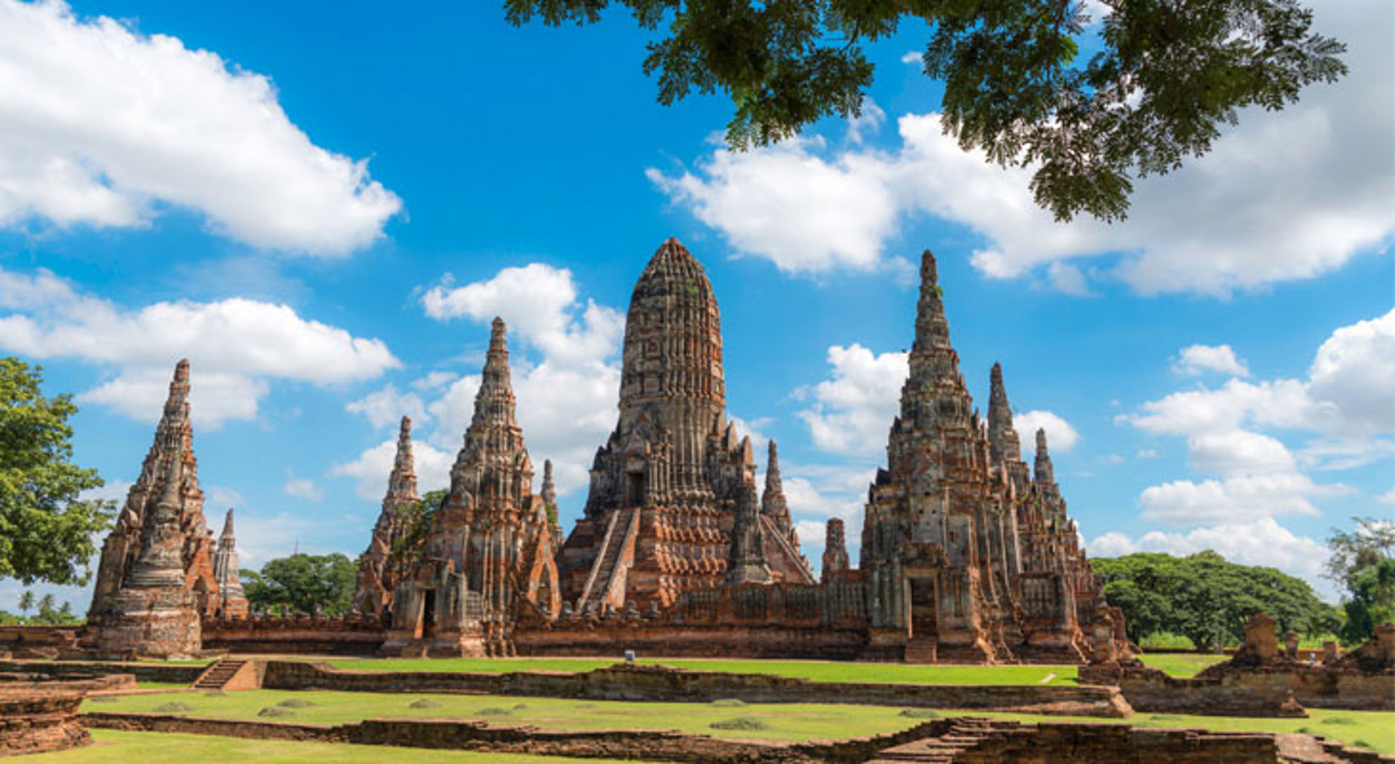 Hstorisch park Ayutthaya Wat Chaiwatthanaram-tempelruïnes in Ayutthaya, Thailand, met hoge prangs onder een blauwe lucht.