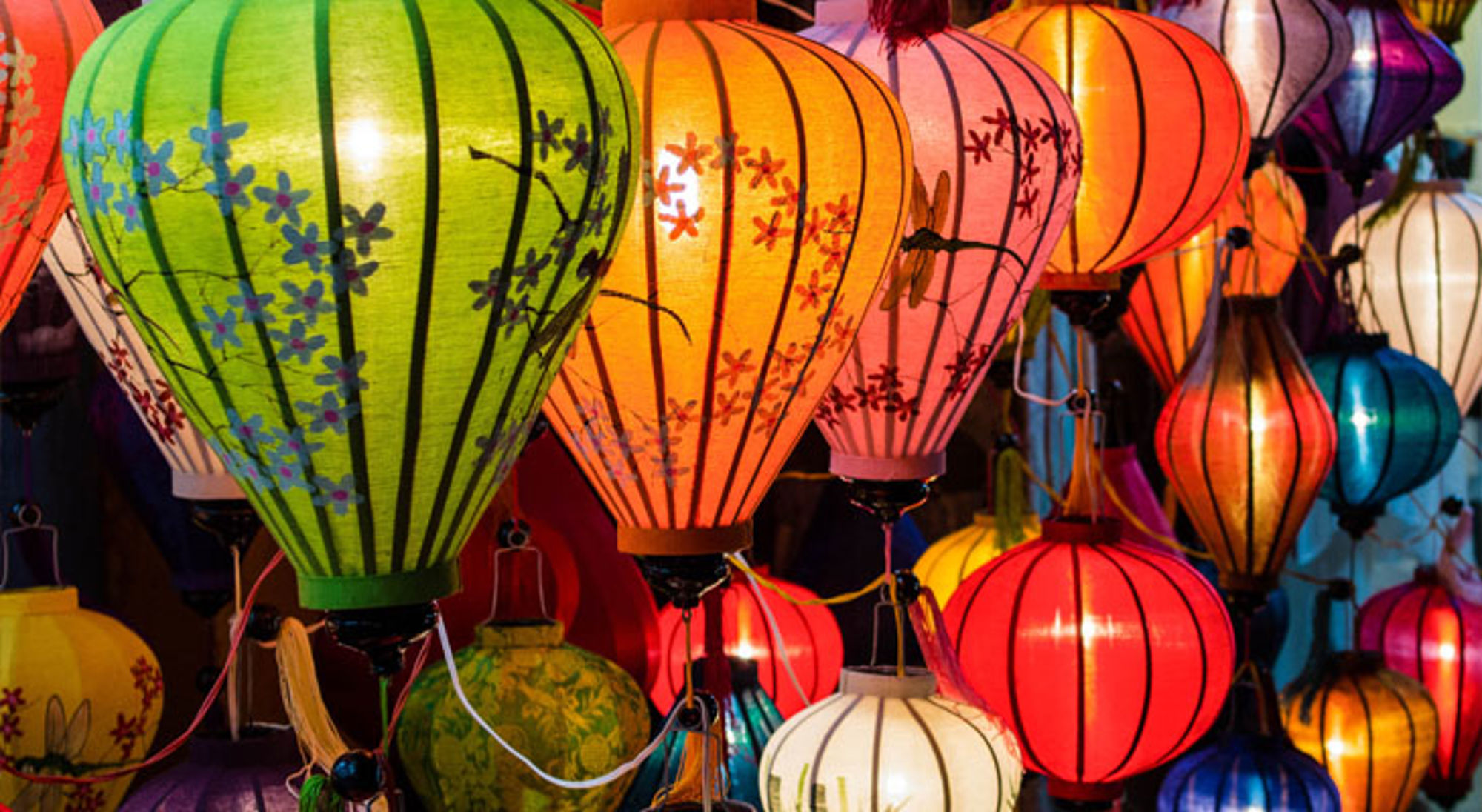 Kleurrijke Vietnamese lampionnen in diverse vormen, hangend op een markt.