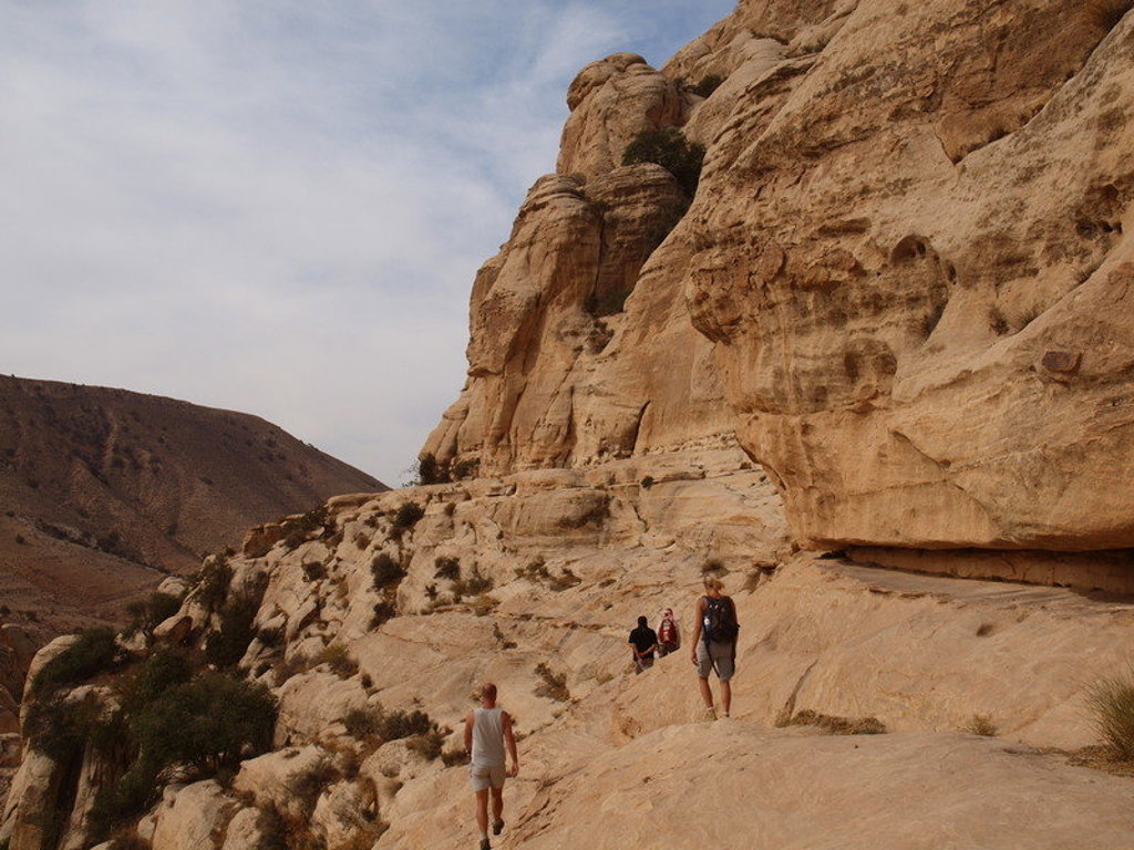 Wandelaars langs zandstenen rotswanden tijdens een 22-35ers reis in Jordanië.