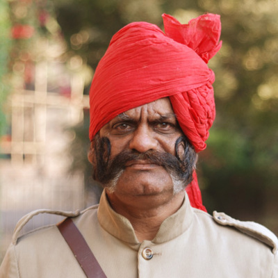 Portret van man met rode tulband en snor tijdens familiereis India en Nepal.