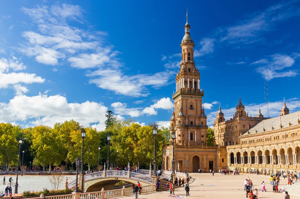 Plaza de España in Sevilla tijdens groepsrondreis Andalusië, met brug en toren onder blauwe lucht.