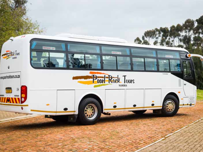 Witte touringcar voor rondreizen in Zuidelijk Afrika, geparkeerd op een weg.