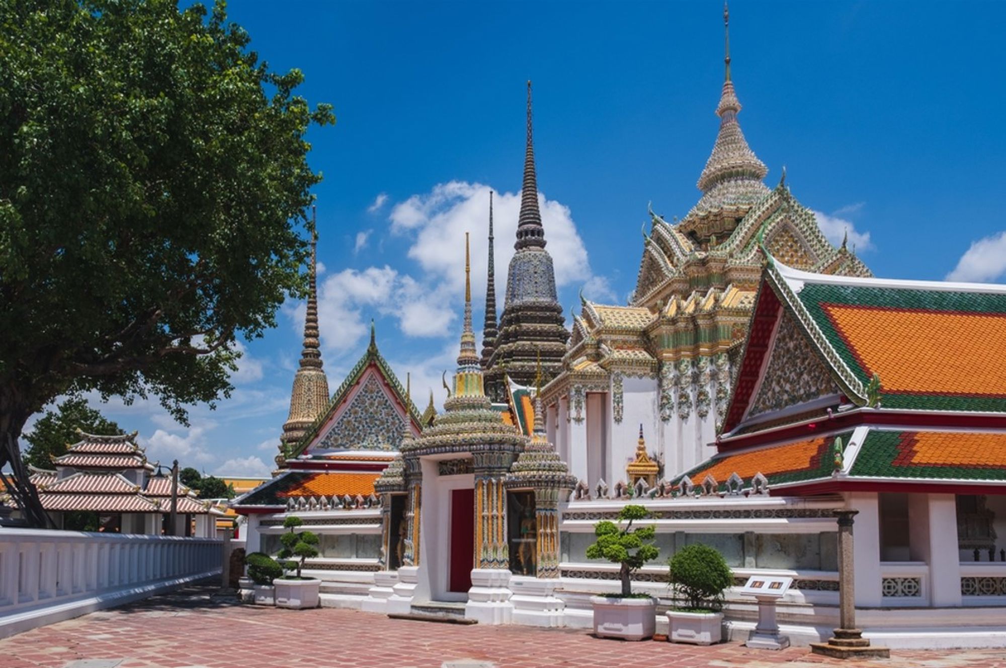 Tempelcomplex Wat Pho in Bangkok, Thailand, met kleurrijke daken en hoge chedi’s onder een blauwe lucht.