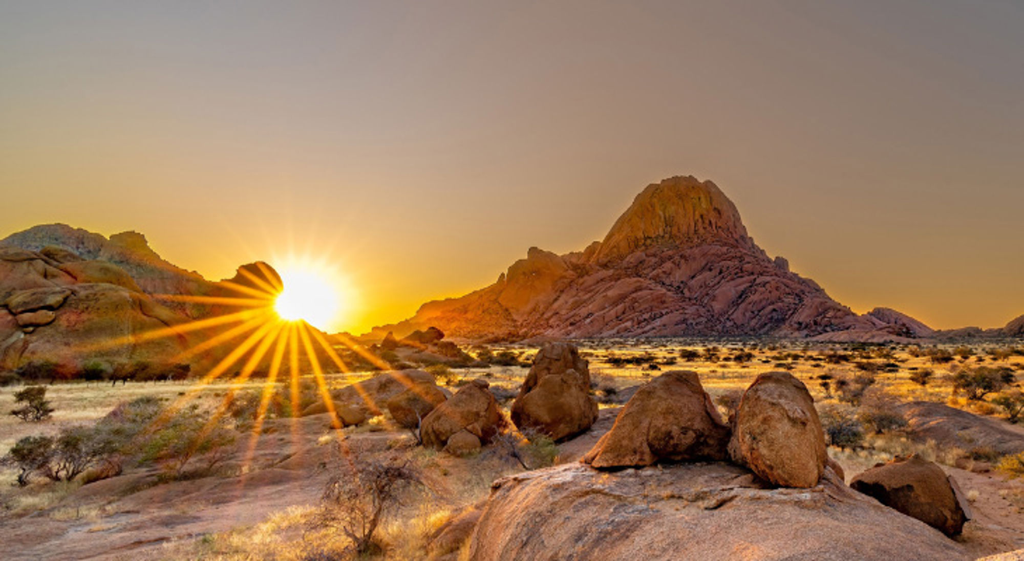 Zonsondergang bij Spitzkoppe met granieten rotsformaties in de Namibische woestijn.