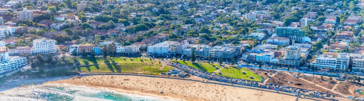 Bondi Beach in Sydney met strand, turquoise zee en skyline op de achtergrond.