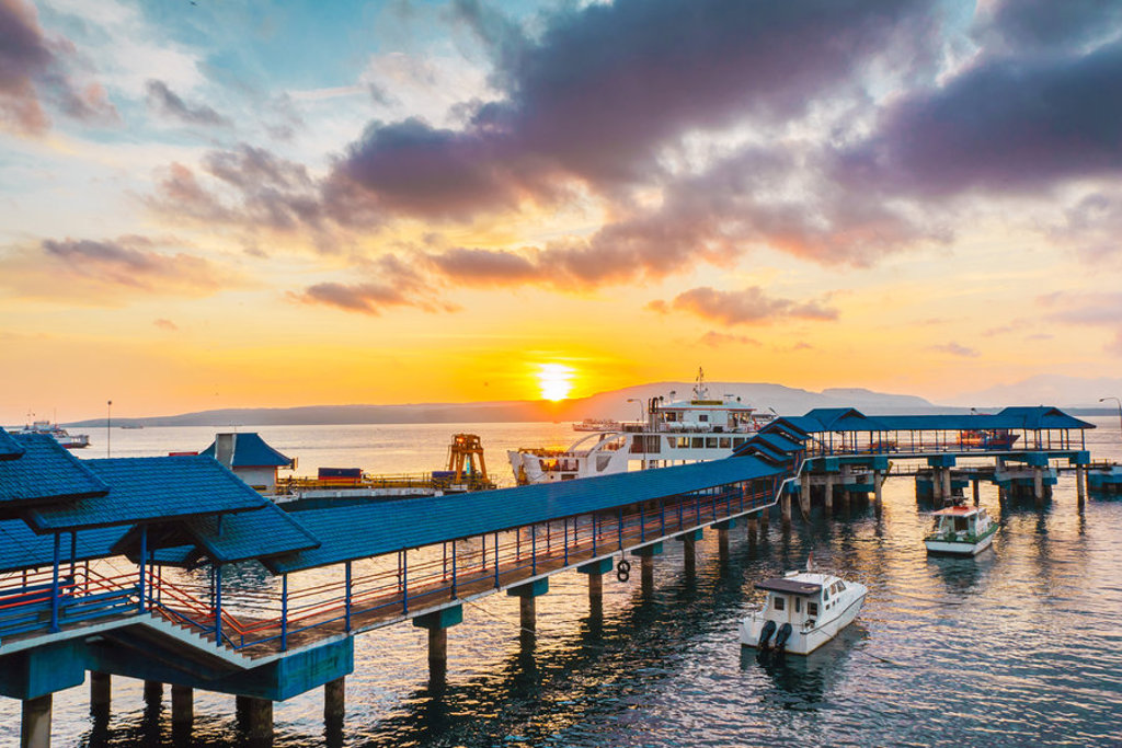 Zonsondergang bij de ferryhaven op Java, met pier en boten op zee tijdens groepsrondreis Java & Bali.