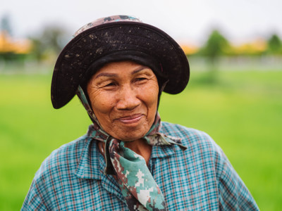 Portret van een rijstboerin met hoed in een groene rijstveld, Route Thailand Noord en Zuid.