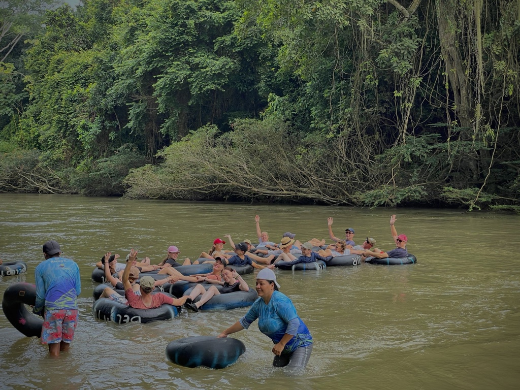 Familiereis Colombia: groep dobbert op binnenbanden over een rivier langs dicht tropisch regenwoud.