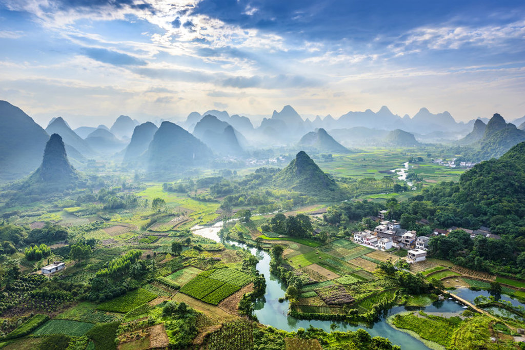 Karstbergen en rijstvelden langs een kronkelende rivier in China tijdens een groepsrondreis.