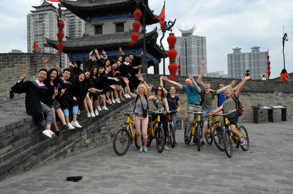 Groepsrondreis China: reizigers met fietsen op de stadsmuur van Xi’an bij een traditionele poort met rode lampions.