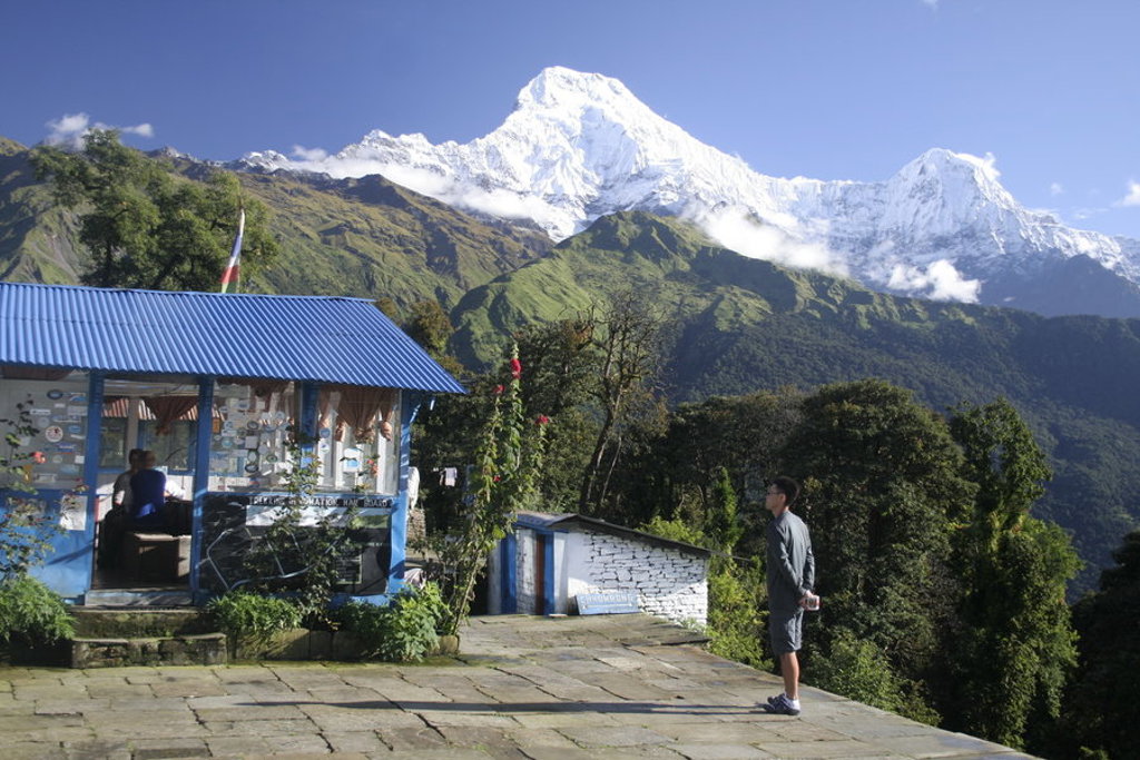 Wandelaar bij een berglodge met uitzicht op de besneeuwde Himalaya tijdens een groepsrondreis Nepal.