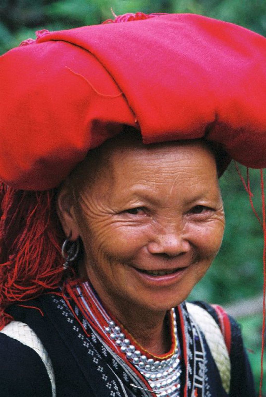 Portret van een glimlachende vrouw in traditionele kleding met rode hoofddoek tijdens een groepsrondreis Vietnam.