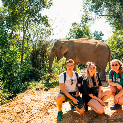 Jongeren tijdens 22-35ers reis Thailand poseren met olifant in de jungle.