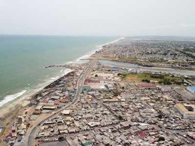 de kustlijn en stad bij Accra, Ghana, met hoofdweg langs het strand en havengebied.