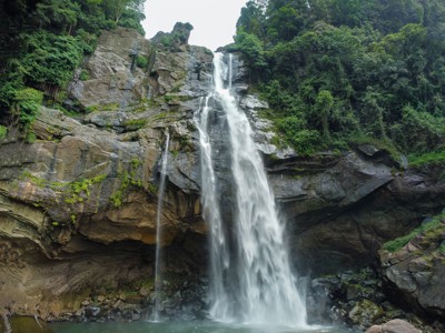 Waterval die langs een rotswand naar een groene poel stroomt in het regenwoud van Sri Lanka.