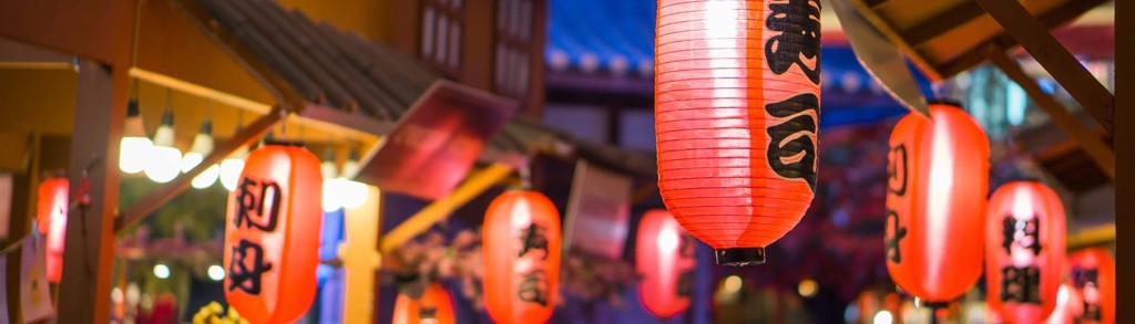 Rode Japanse lantaarns met kalligrafie in een sfeervolle straat bij avond, passend bij een groepsrondreis Japan.