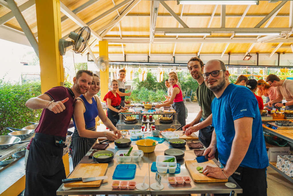 Groep 22-35ers bereidt Thaise gerechten tijdens kookworkshop op rondreis in Thailand.