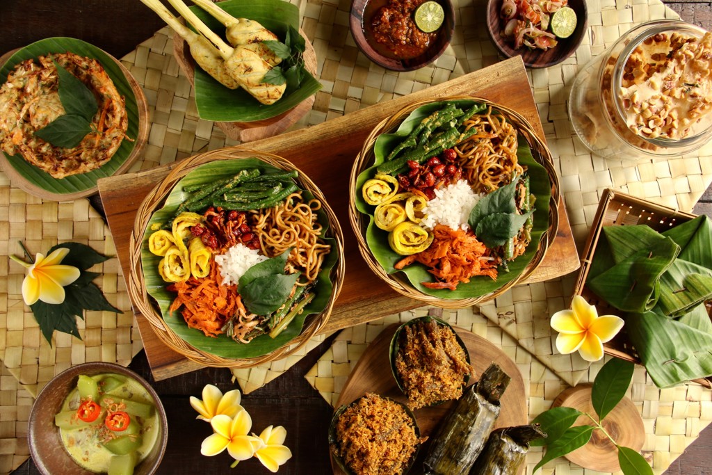 Balinese rijsttafel met noedels, rijst en saté, geserveerd op bananenblad tijdens 22-35ers reis Bali en Lombok.