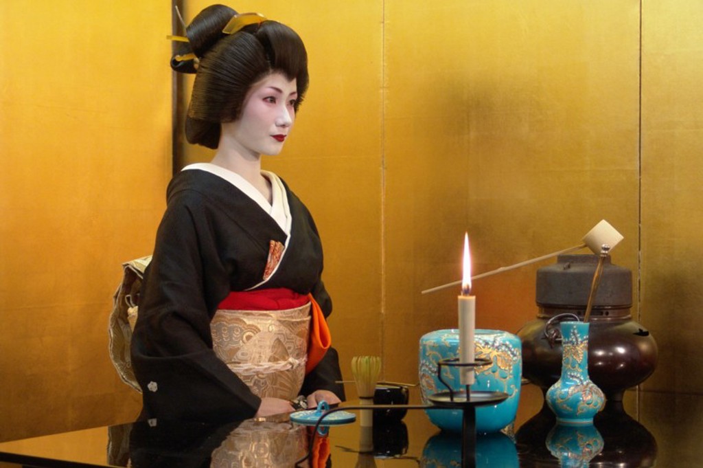 Japanse geisha in kimono bij een traditionele theeceremonie met kaars en theeset in Japan.