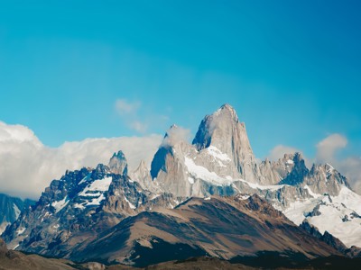 Fitz Roy-bergmassief in Patagonië met besneeuwde pieken onder een helderblauwe lucht.