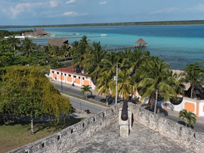 Uitzicht vanaf het fort in Bacalar op de Lagune van Zeven Kleuren met palmbomen en turquoise water.