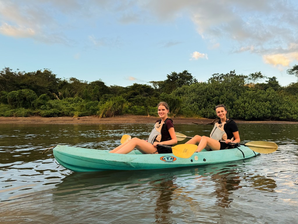 Twee reizigers kajakken op een rustige rivier in Costa Rica tijdens een 22-35ers groepsreis.