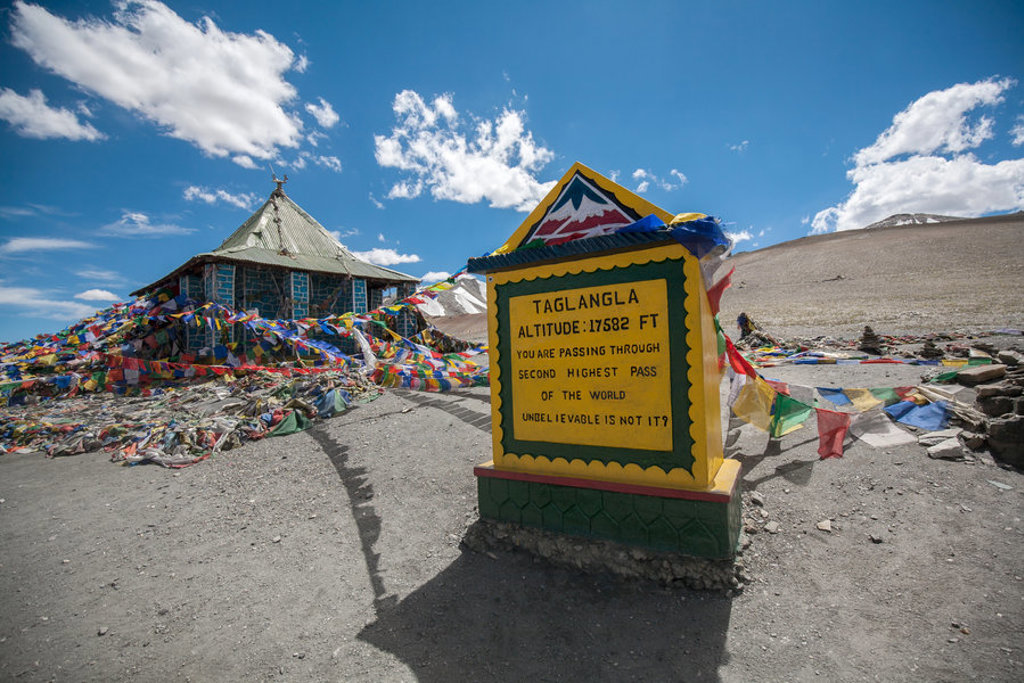 Bord bij de Taglang La-pas in Ladakh, met kleurrijke gebedsvlaggen in het hooggebergte.