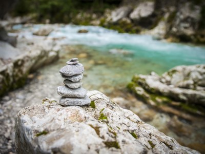 Gestapelde stenen op rots aan turquoise rivier in Slovenië.
