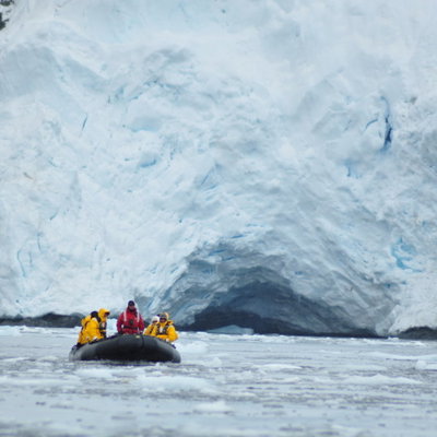 Zodiacboot met reizigers voor een ijsgrot in Antarctica tijdens de groepsrondreis Crossing the Circle.