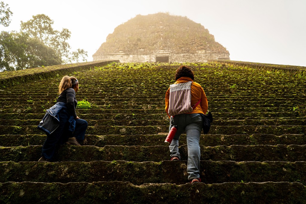 Reizigers beklimmen de trappen van een Maya-tempel in Guatemala tijdens een familiereis Guatemala en Belize.