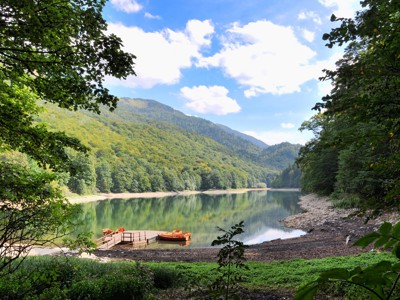 Groen bergmeer in Nationaal park Biogradska Gora in Montenegro, met houten steiger en roeiboot.