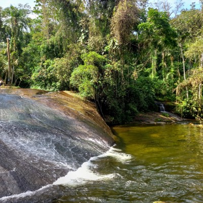 Tobogã waterval met natuurlijke rotsglijbaan en helder Tarzan’s zwembad, omringd door tropisch groen.