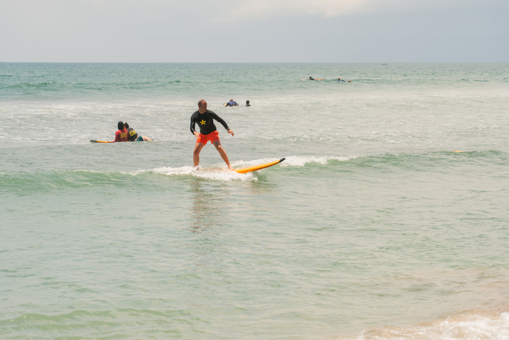 Surfer op een kleine golf bij het strand tijdens een 22-35ers reis in Indonesië, Bali en Lombok.