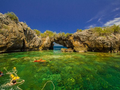 Snorkelen in helder water bij een rotsboog aan de kust van Thailand.