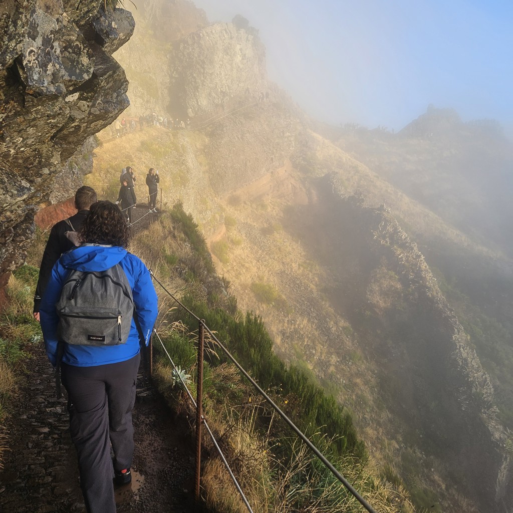 Wandelaars op bergpad langs steile kliffen in de mist op Madeira, Portugal.